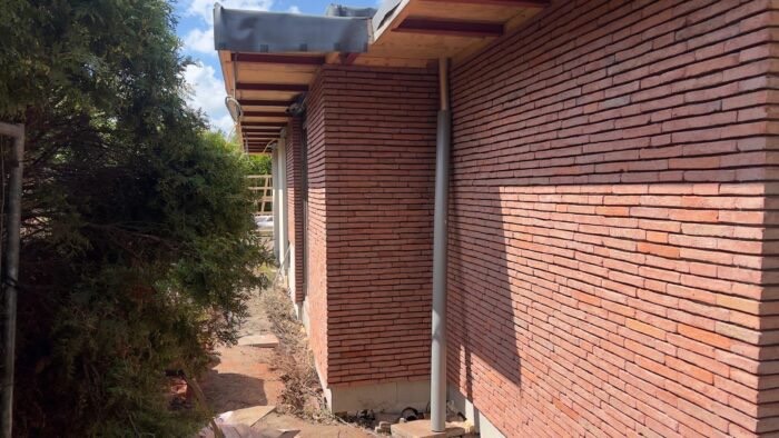 Gevel met rood-genuanceerde steenstrips onder een dakoverstek