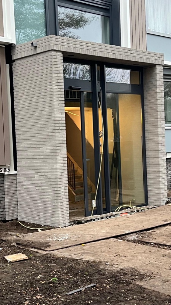 Traphuis-entree in Utrecht met lichtgrijze minerale steenstrips, recht van voren gezien