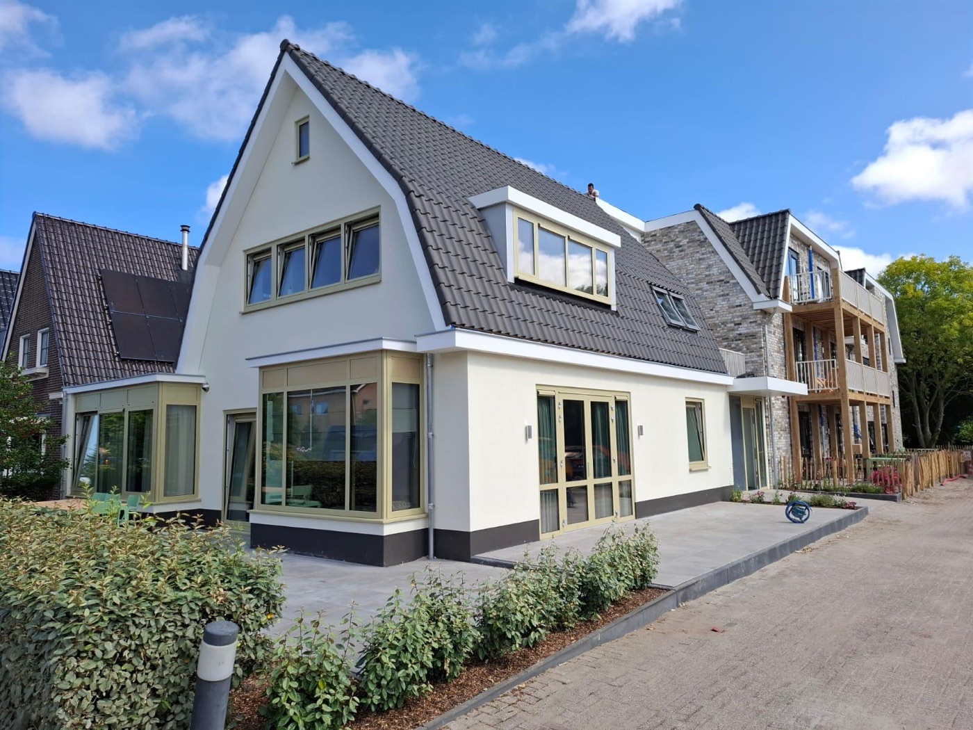 Woning op Texel na de buitengevelisolatie, met een witte sierpleistergevel en een donkere plint