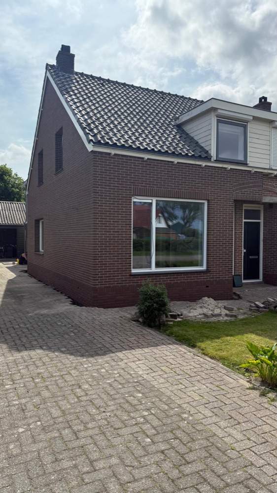 Woning in Breezand na het werk, met een steenstripsgevel en een groot wit kozijn aan de voorzijde